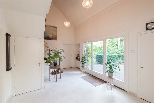 Empty hallway before renovation, showing worn flooring, plain walls, and an outdated entrance. A basic door and minimal natural light suggest potential for modernization
