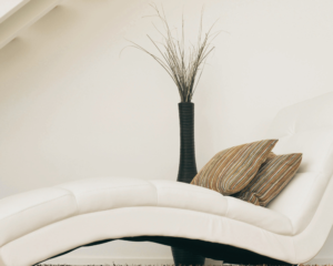 Minimalist white lounge long chair with plush neutral cushions beside a tall ceramic vase in a serene luxury living space